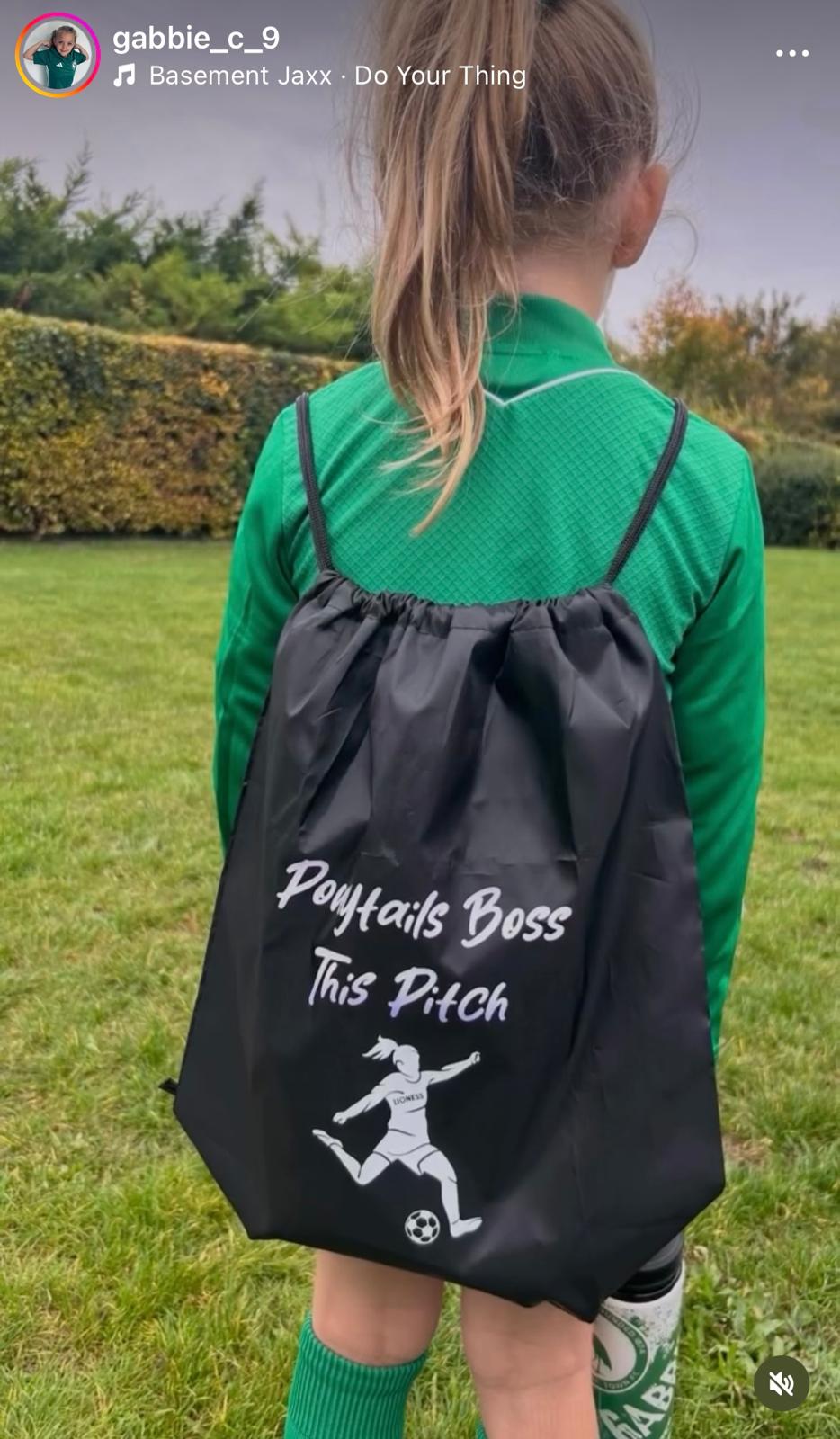 Person wearing a black drawstring bag with text and graphics on a grassy field