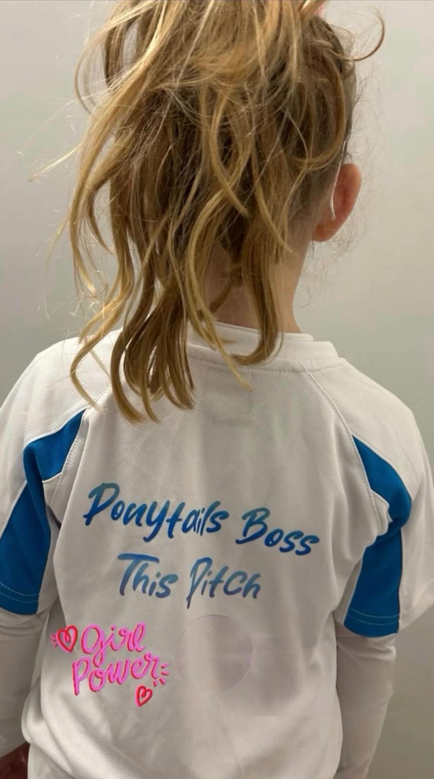 Child wearing a shirt with text and graphics, standing against a plain background